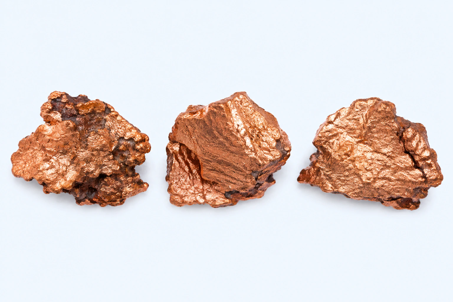 Three elemental copper specimens with restrained reddish metallic surfaces and minor dark oxidation.