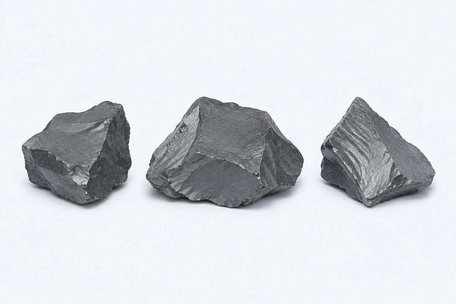 Three gray elemental selenium specimens with dark steel-gray angular fracture surfaces.