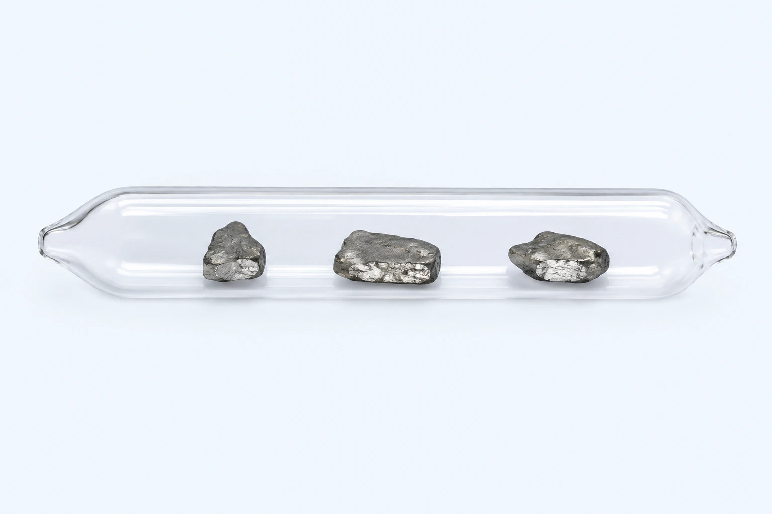 A sealed clear ampoule containing three low gray elemental thallium specimens with bright cut faces.